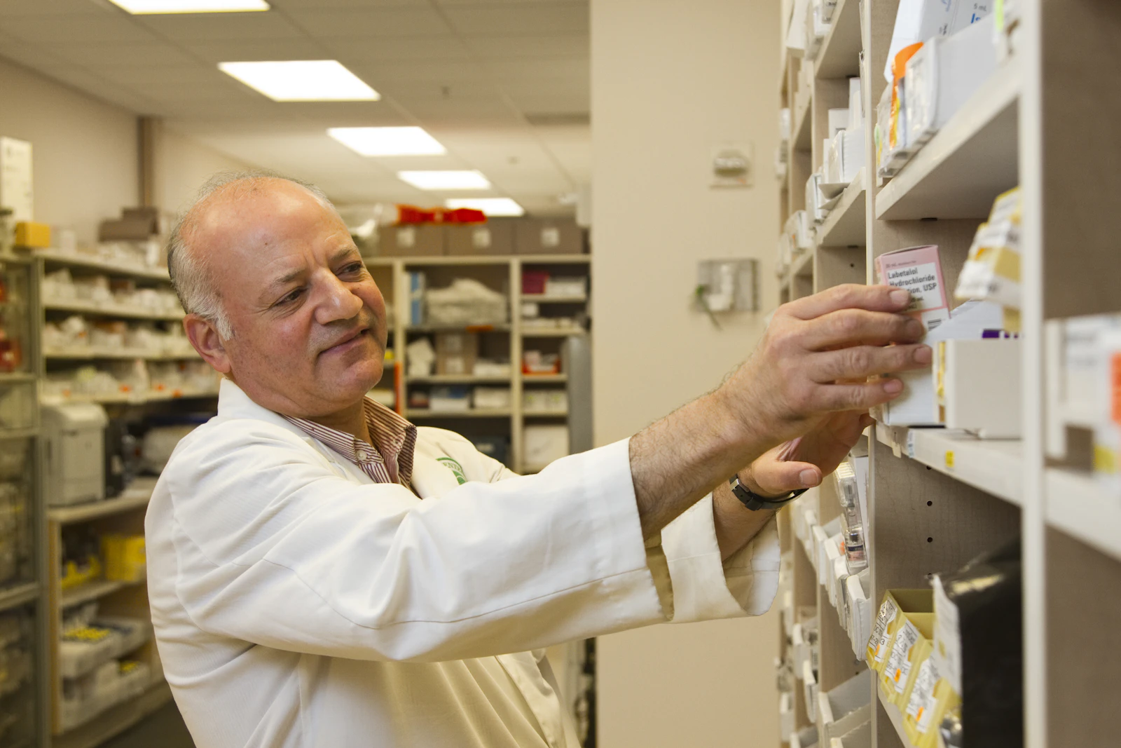 A pharmacist selecting a medicine in a pharmacy; illustrative photograph, not a COGNIFUL team member.