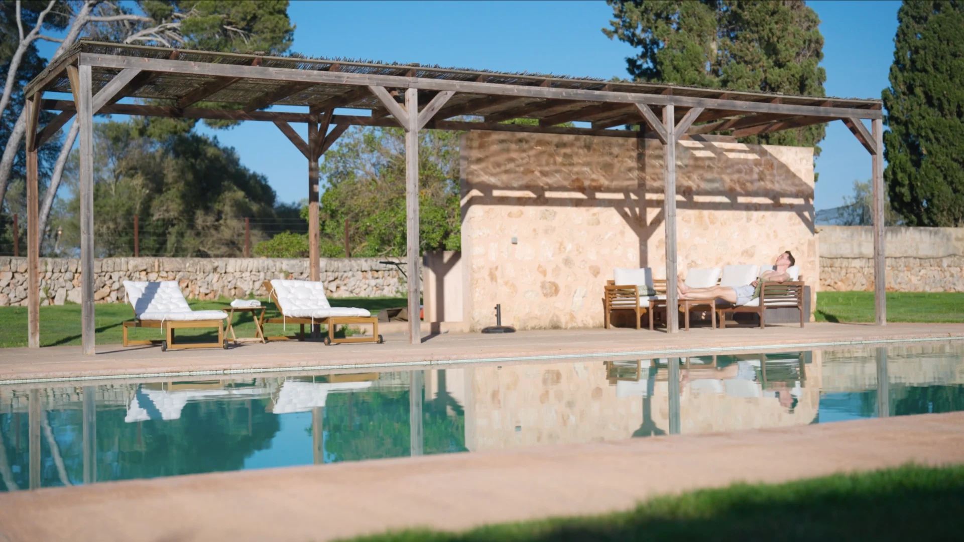 Poolside pergola with lounge chairs beside a swimming pool